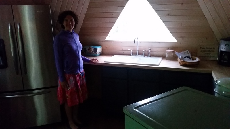A woman smiles in a kitchen with a triangle skylight.