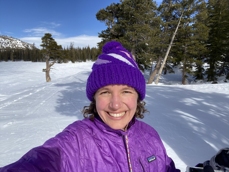 A skier in all purple with a big smile