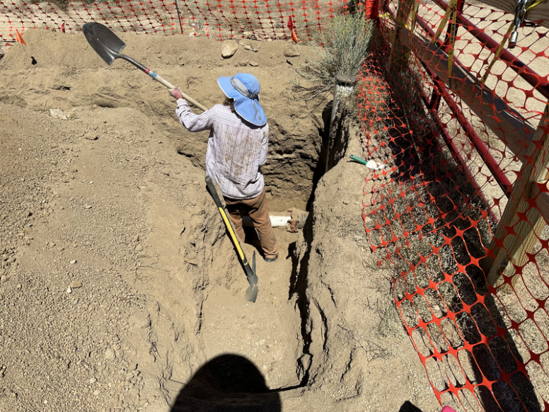 A woman tosses dirt over her shoulder from a 5' deep hole