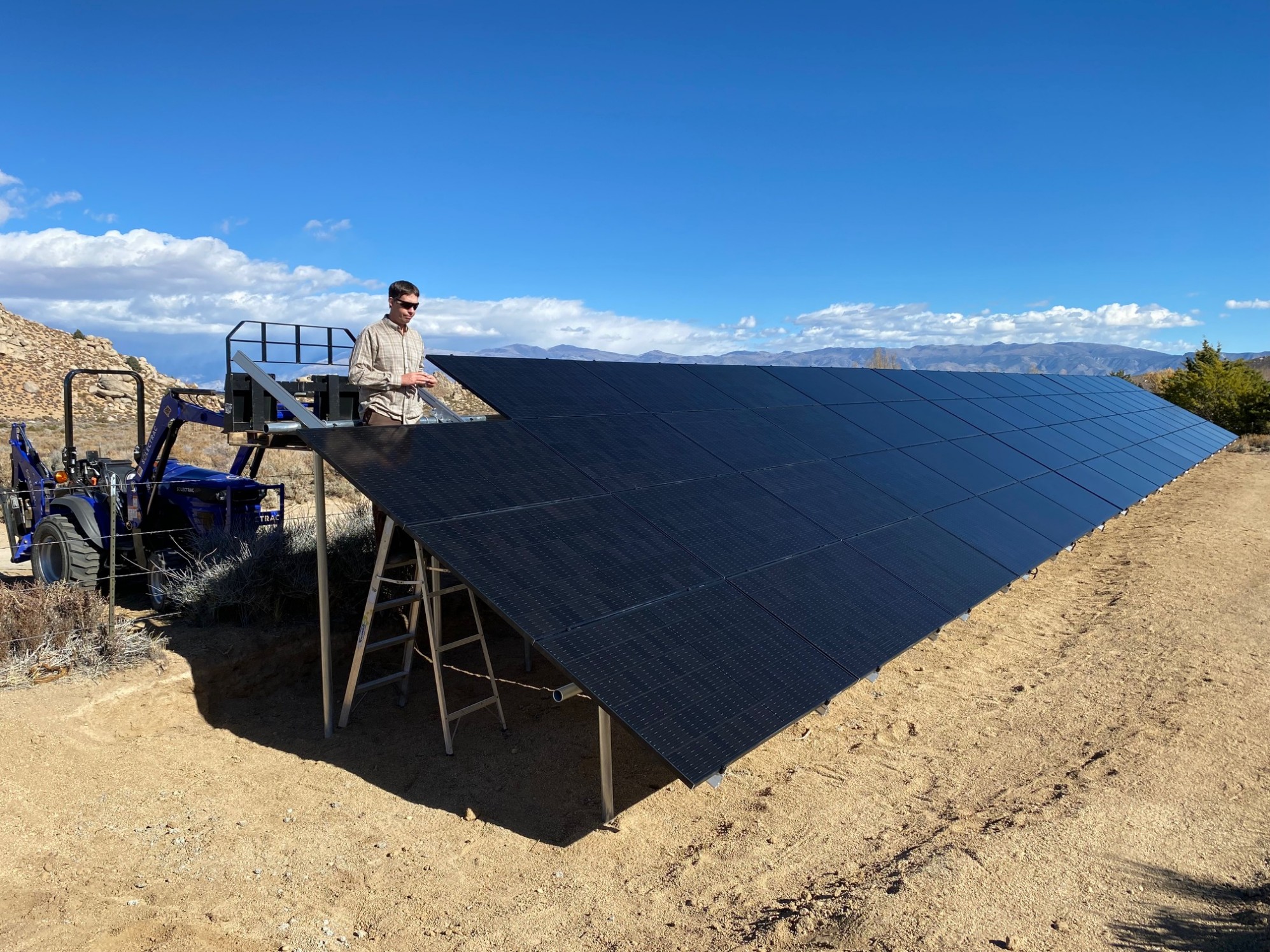 A man standing where a final solar panel will be to give scale to the large array