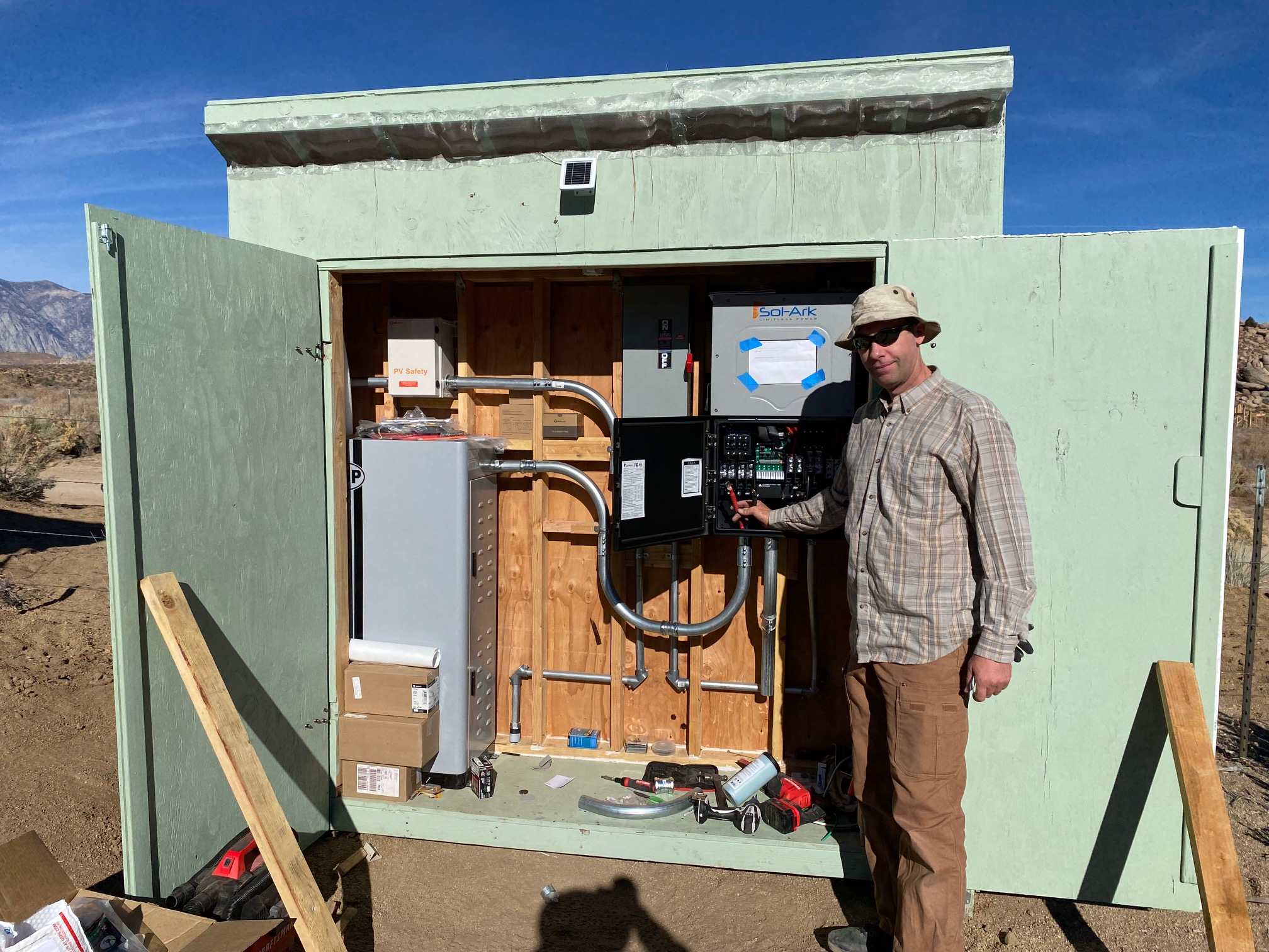 A man shows off an inverter in a temporary power shed