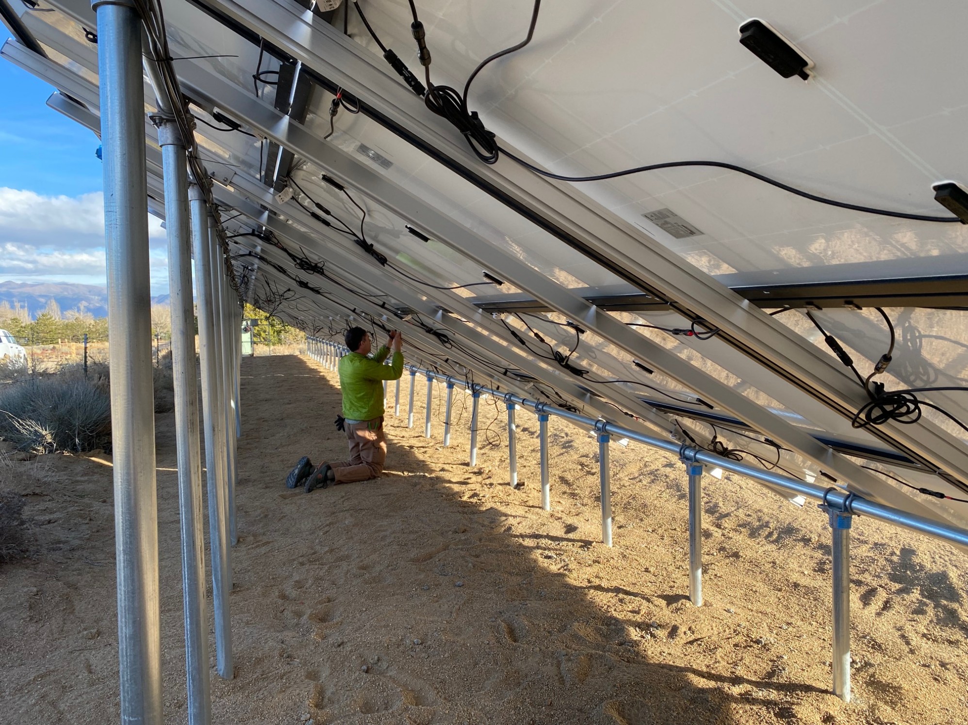 A man connecting wires behind a solar array