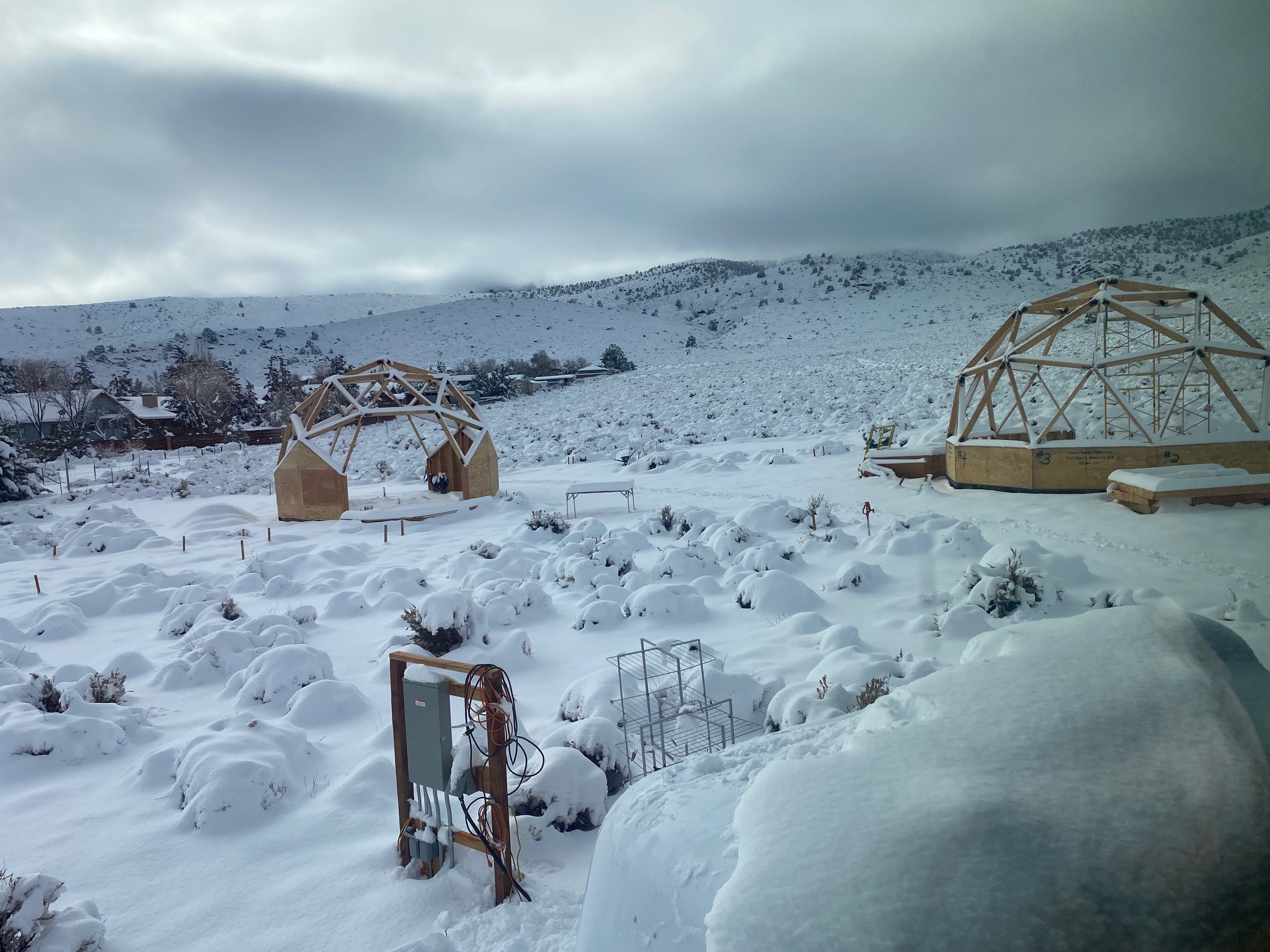 2 partially constructed geodesic dome buildings in a snowy landscape