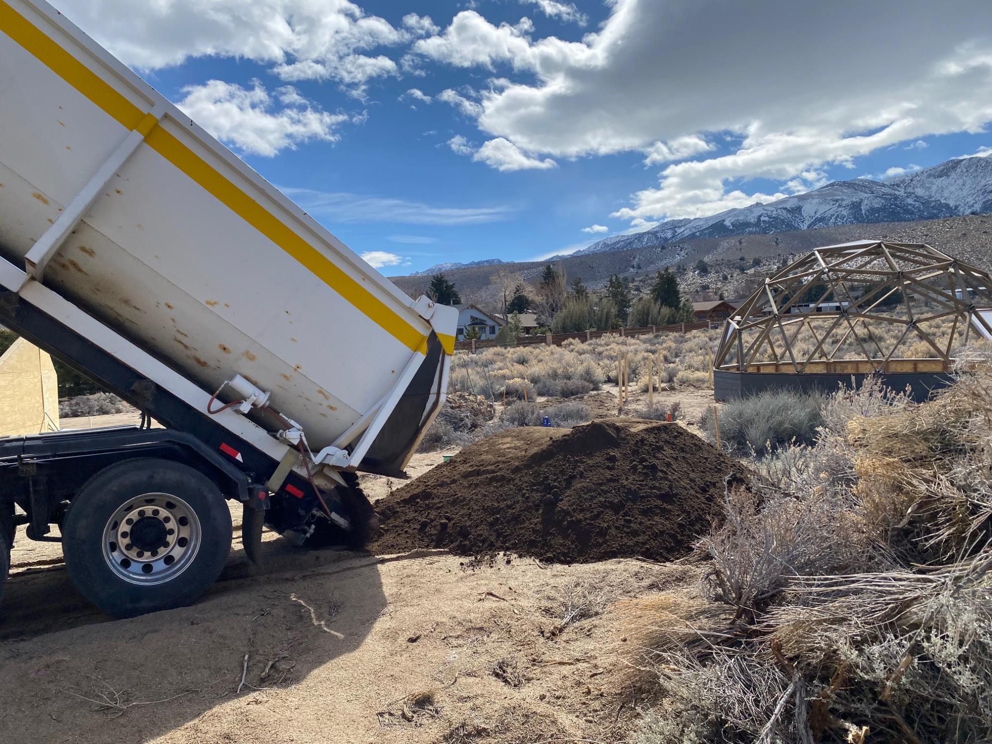 A truck dumping garden soil on the ground