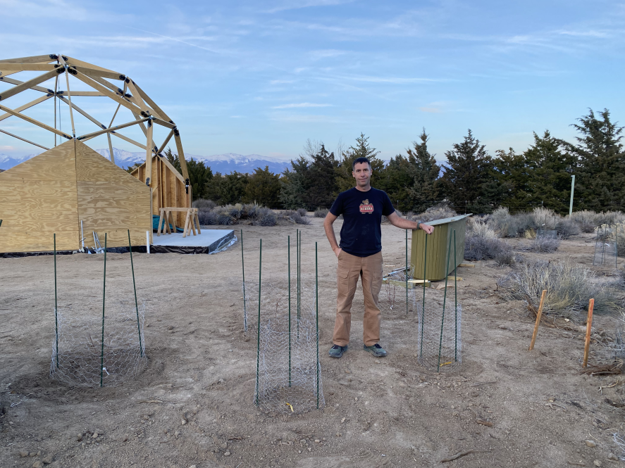 A man posing by tiny plants in cages