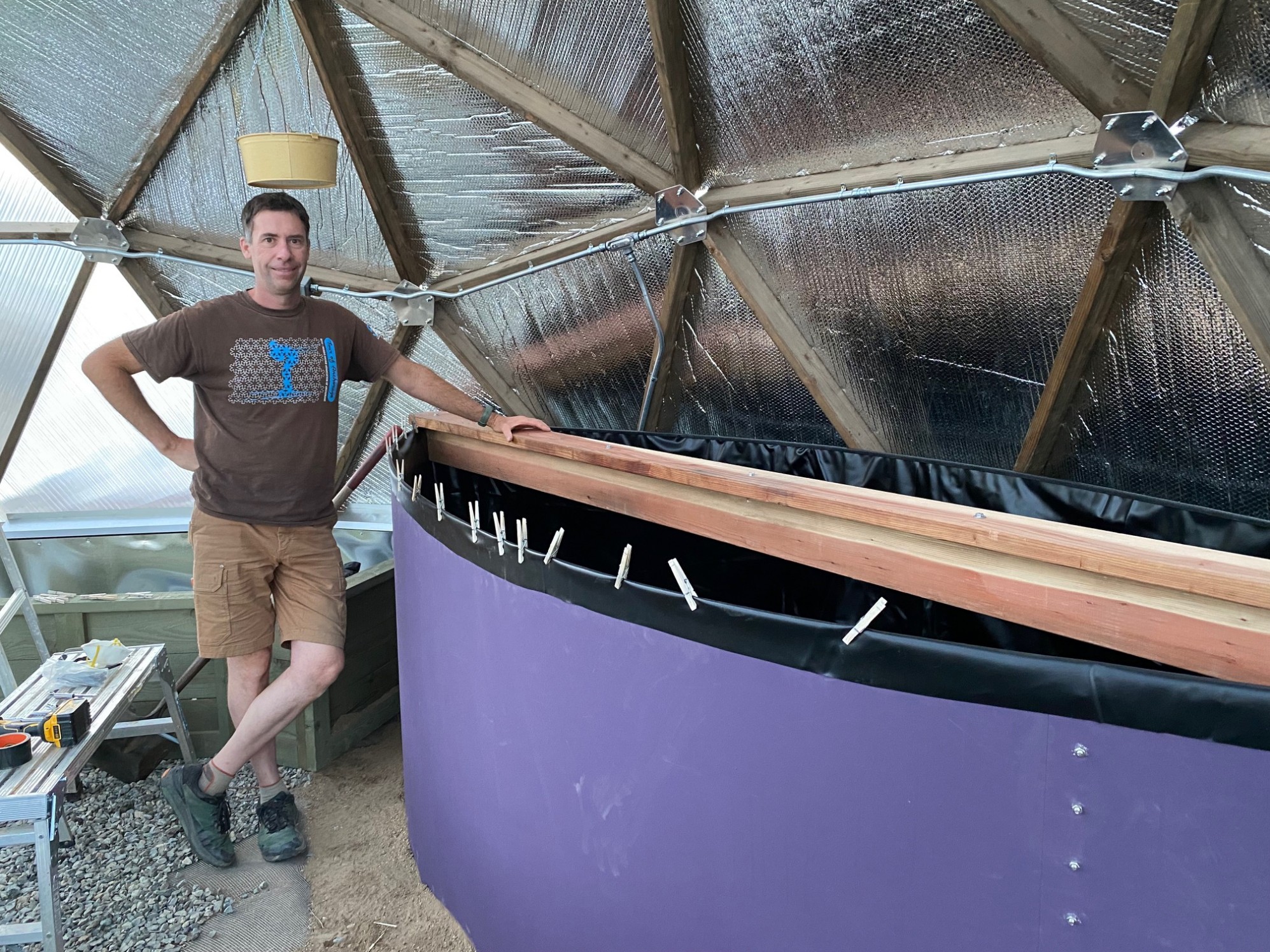 A man posing by an indoor pond with redwood planks on top.