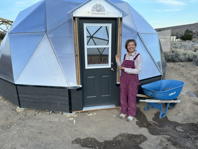 A woman posing near a gray door in a dome