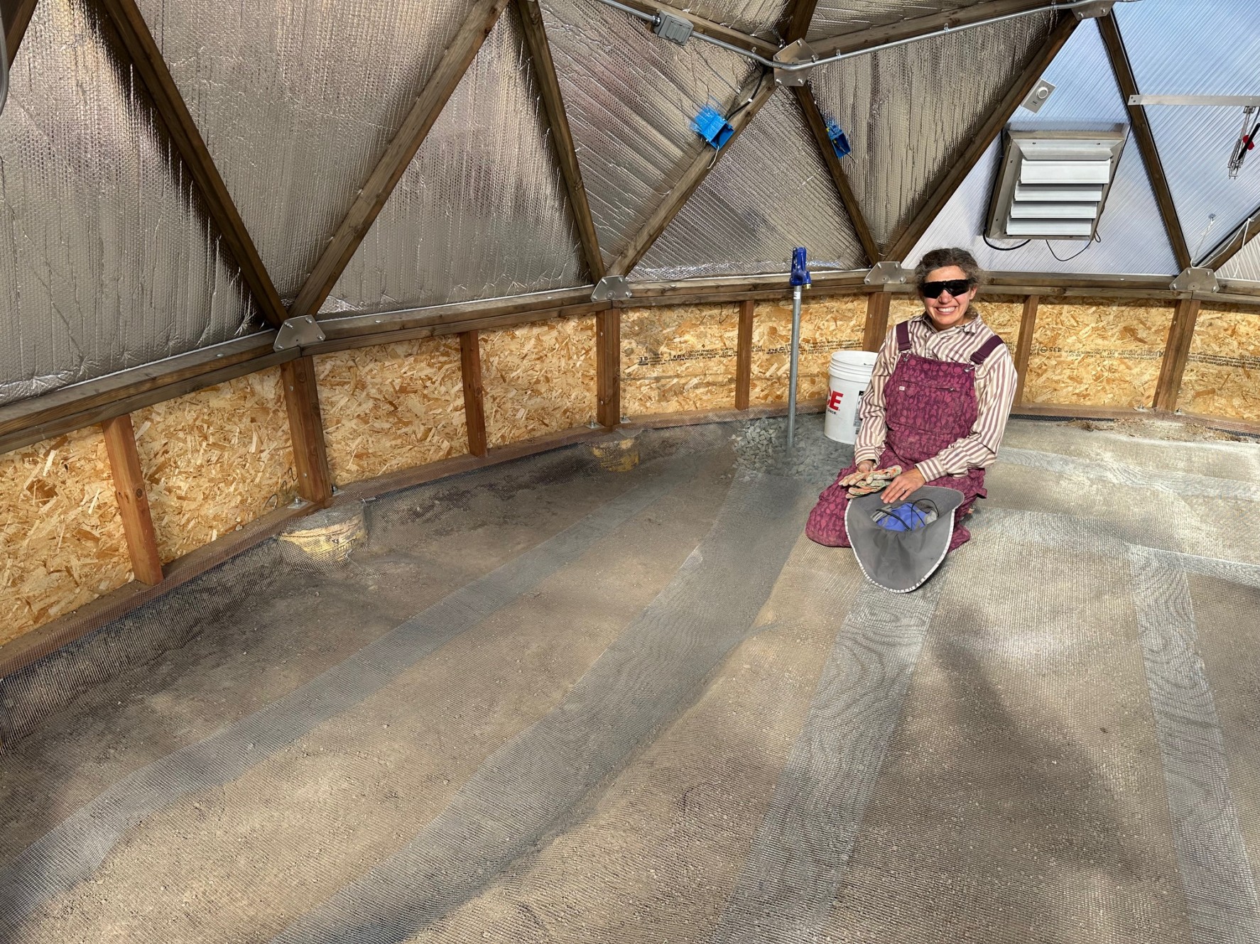 A woman kneeling on a floor covered in hardware cloth