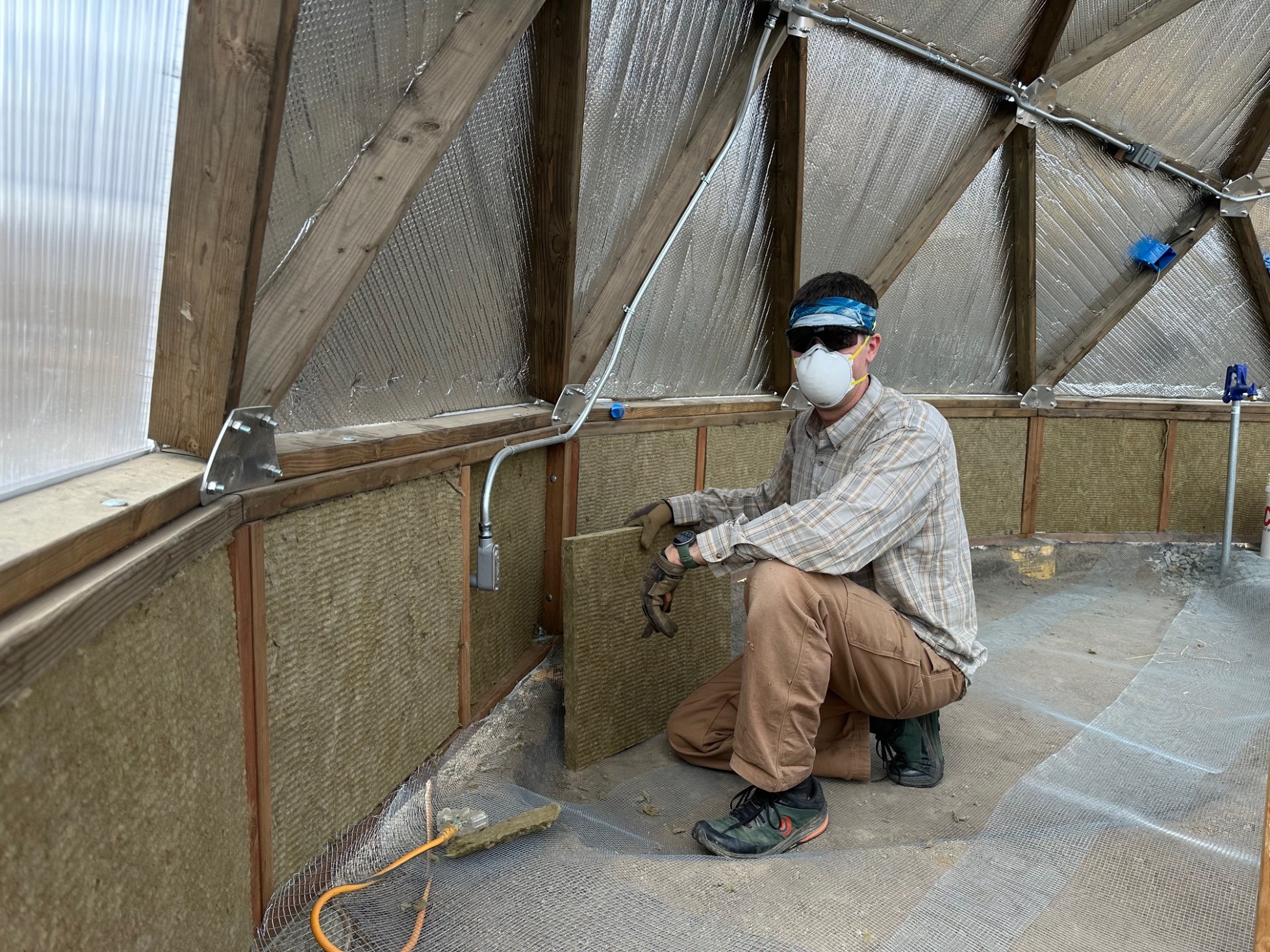 A man in a dust mask installing insulation