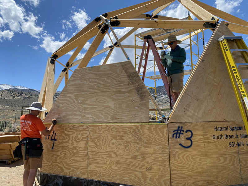 2 men working on either side of a triangle on a geodesic dome