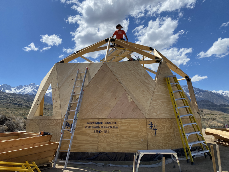 Man stands on scaffolding at top of geodesic dome