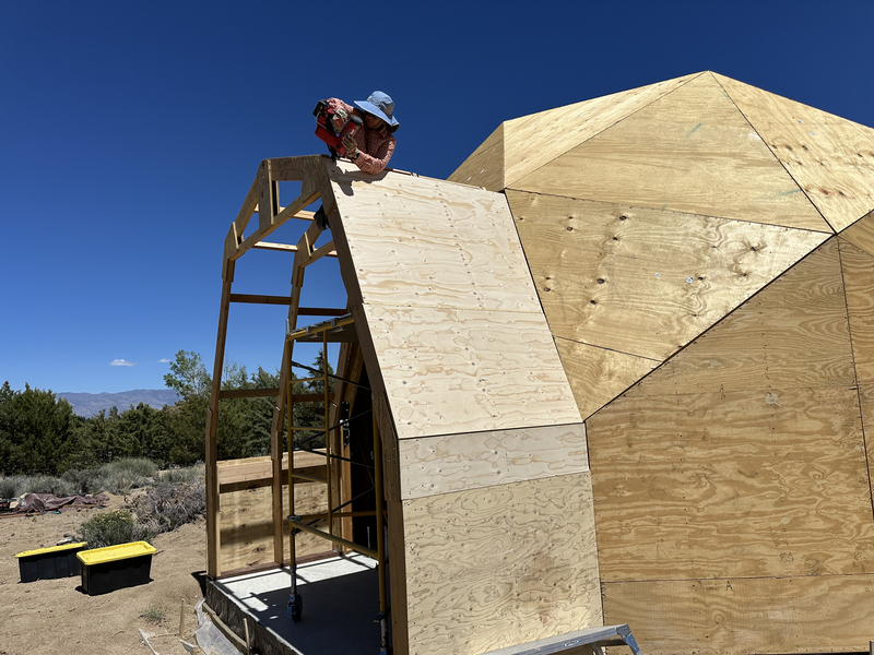 A woman nails a piece of plywood to a dome extension