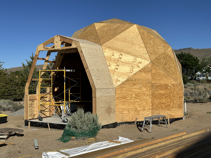 A partially completed geodesic dome with an extention