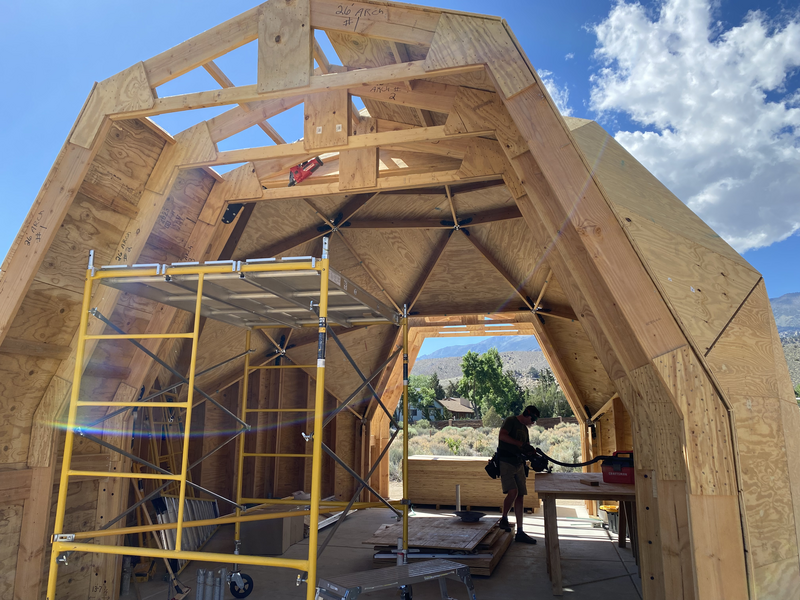 Looking into a partially completed geodesic dome with a person cutting plywood inside